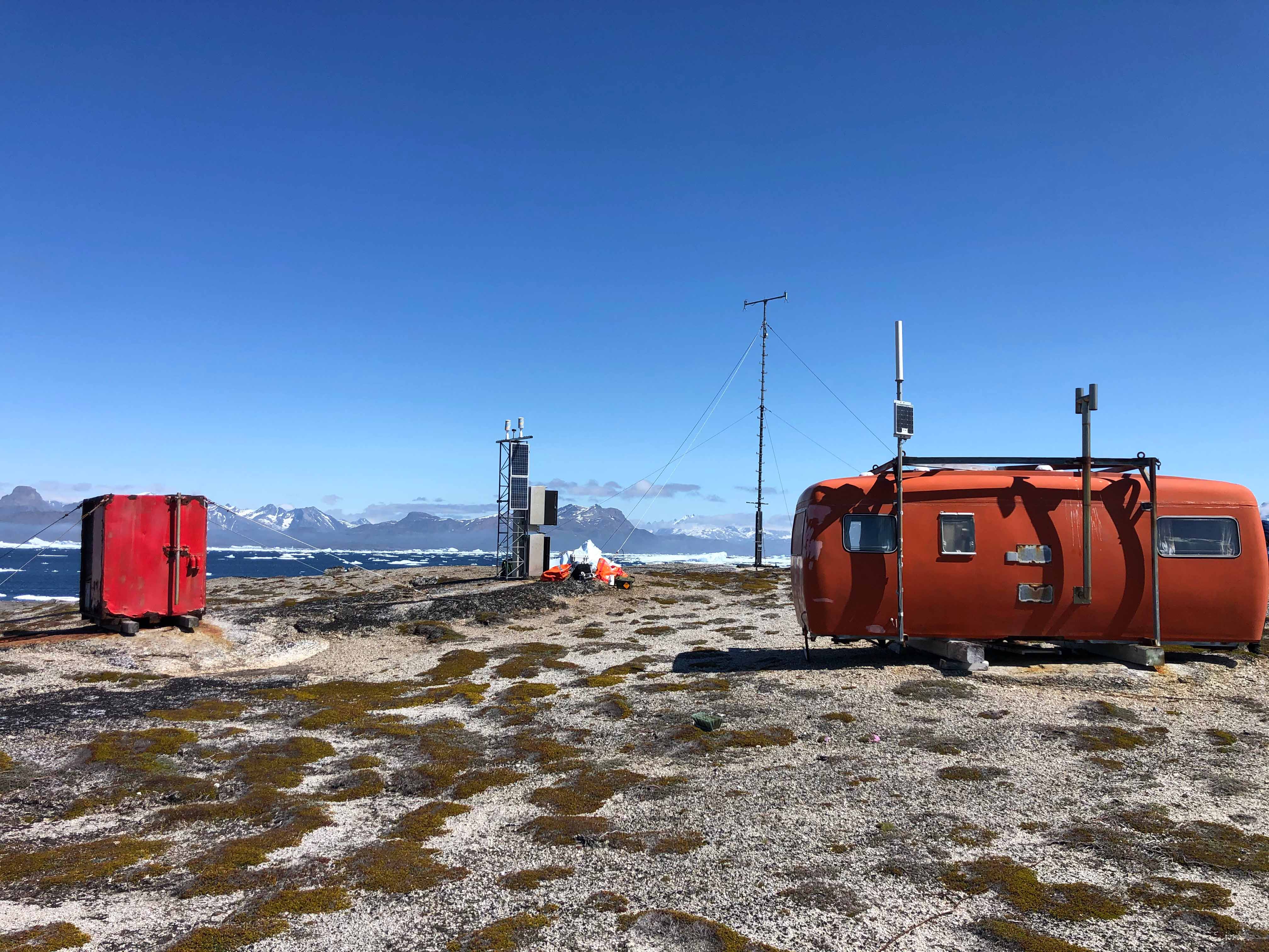 Orange målestationer og antenne, med bjerge i baggrunden - Foto: Lasse Nielsen, DMI