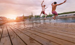 to mænd hopper fra badebro, mens solen går ned