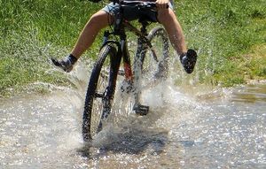 Person cykler gennem stor vandpyt