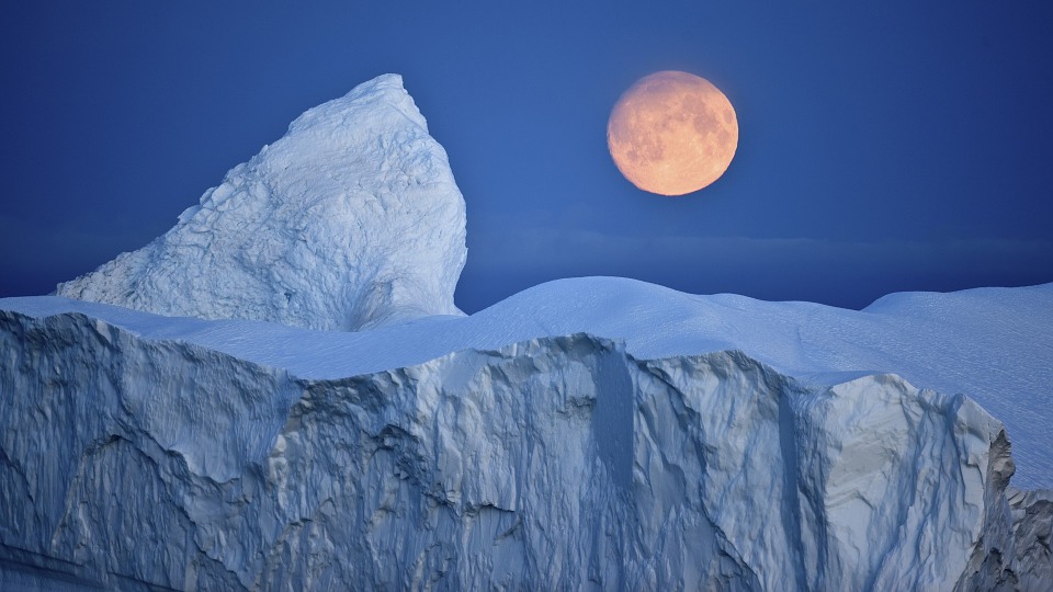 Orange måne over isbjerg