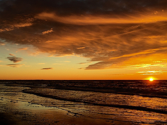 Solnedgang over havet med orange himmel